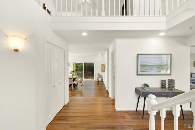 hall with a towering ceiling, light wood-style floors, and baseboards