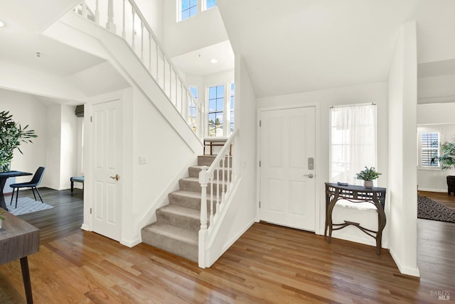 entryway featuring baseboards, stairs, a high ceiling, and wood finished floors