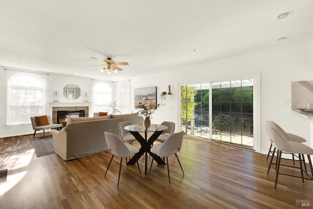 dining space featuring wood finished floors, a glass covered fireplace, a ceiling fan, and recessed lighting