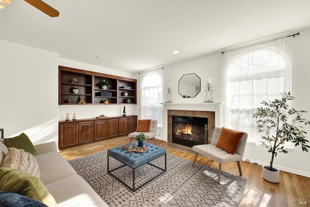 living room featuring light wood-type flooring, baseboards, recessed lighting, and a tile fireplace