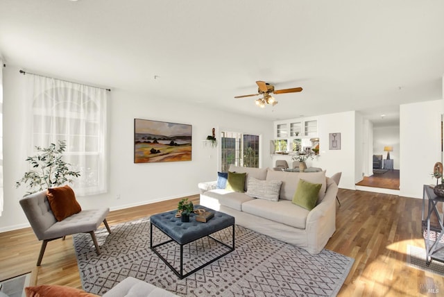 living room featuring ceiling fan, baseboards, and wood finished floors