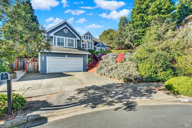 view of front of property featuring a garage, driveway, stairway, and fence