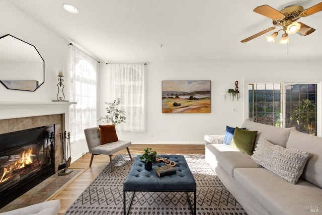 living area with recessed lighting, a tiled fireplace, a ceiling fan, wood finished floors, and baseboards