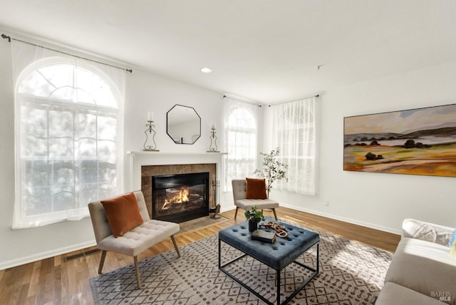 living area featuring recessed lighting, visible vents, wood finished floors, a tile fireplace, and baseboards