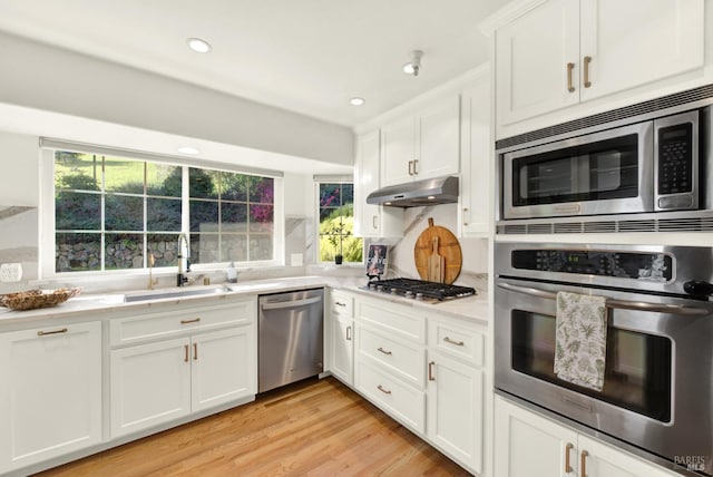 kitchen featuring under cabinet range hood, stainless steel appliances, a sink, white cabinetry, and light countertops