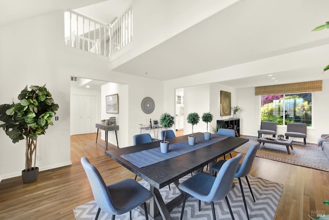 dining room with a high ceiling, wood finished floors, and baseboards