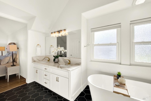 bathroom with a sink, a freestanding bath, vaulted ceiling, and a wealth of natural light