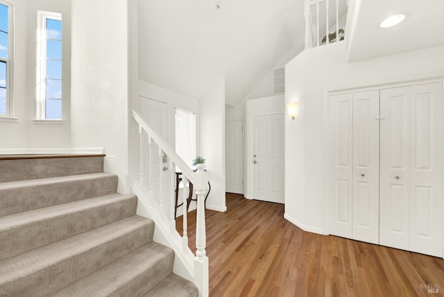 foyer with light wood-type flooring, baseboards, and stairway