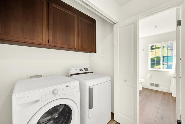 washroom with cabinet space, visible vents, baseboards, light wood-style flooring, and independent washer and dryer