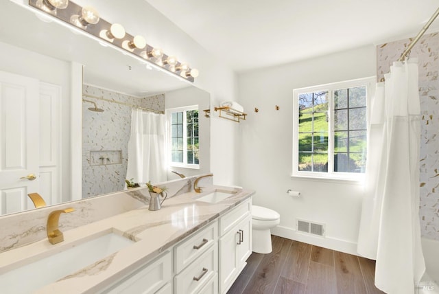 bathroom featuring toilet, visible vents, a sink, and wood finished floors