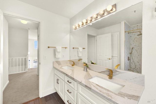 bathroom with double vanity, a shower, a sink, and wood finished floors