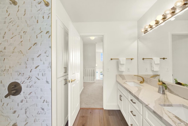 bathroom with a tile shower, wood finished floors, a sink, and visible vents