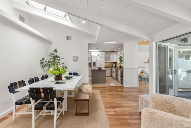 dining space with light wood-style floors, visible vents, plenty of natural light, and lofted ceiling with beams