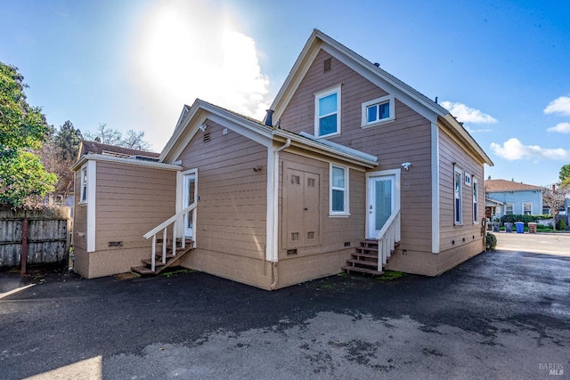 rear view of property featuring entry steps, crawl space, and fence