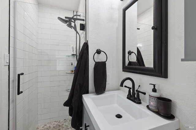 full bath featuring a sink, a shower stall, and a textured wall