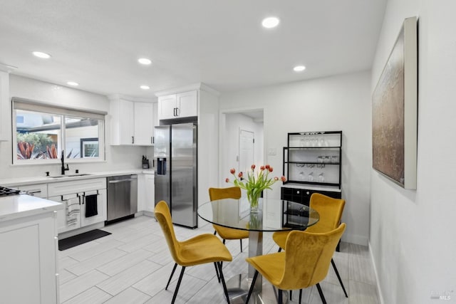 kitchen featuring recessed lighting, light countertops, appliances with stainless steel finishes, white cabinets, and a sink