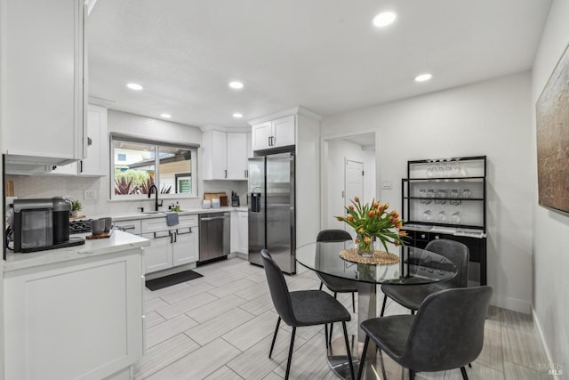 kitchen featuring white cabinets, a sink, light countertops, recessed lighting, and stainless steel appliances