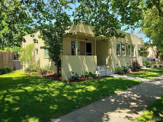 view of front facade with a front lawn, fence, and stucco siding