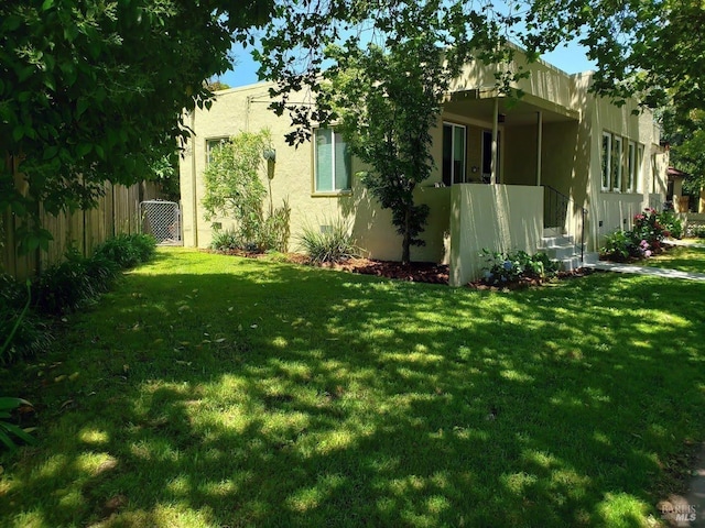 exterior space featuring fence, a lawn, and stucco siding