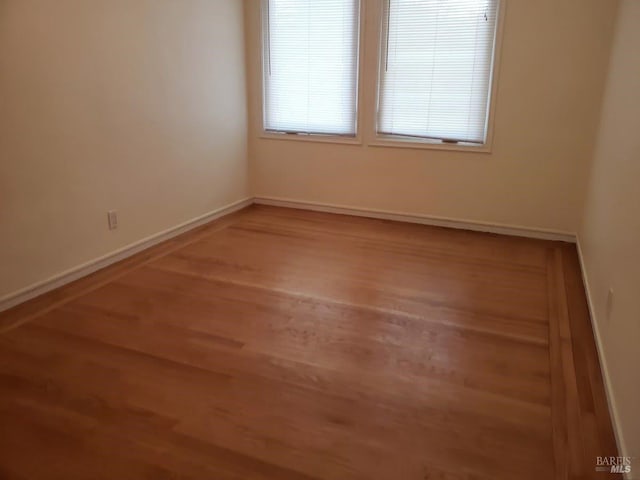 unfurnished room with baseboards and wood finished floors