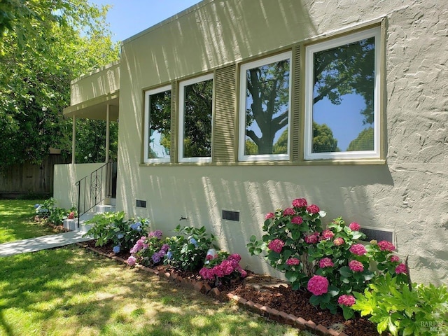 view of property exterior featuring crawl space, a lawn, fence, and stucco siding