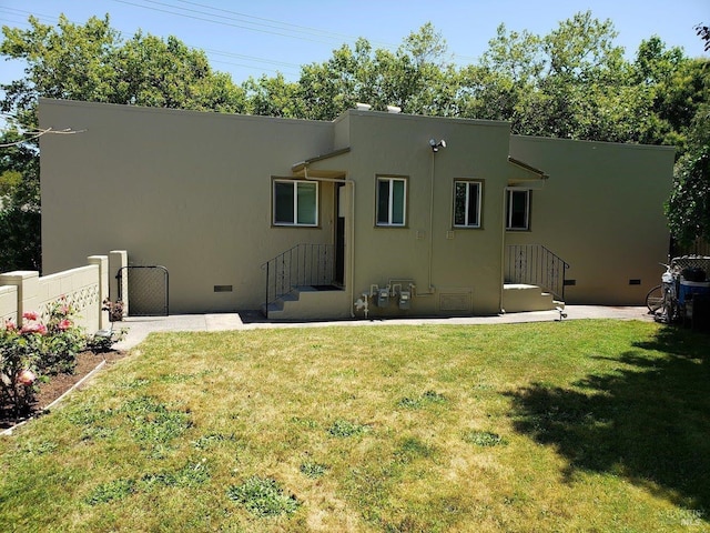 rear view of house with crawl space, fence, a lawn, and stucco siding