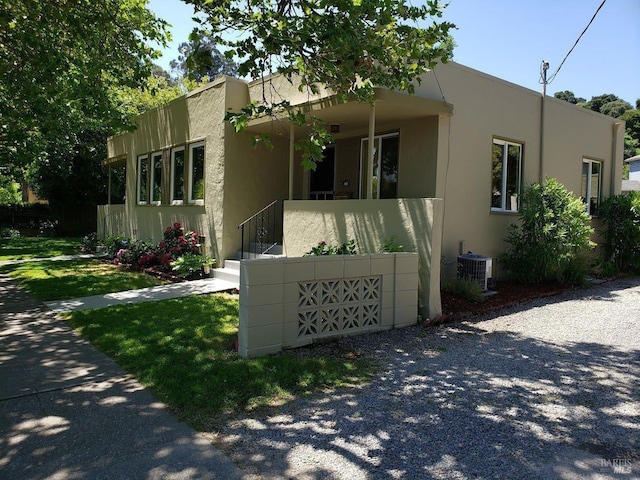 view of front of property with covered porch, central air condition unit, and stucco siding