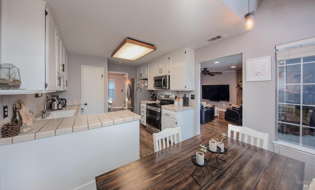 dining space with a ceiling fan, visible vents, and wood finished floors