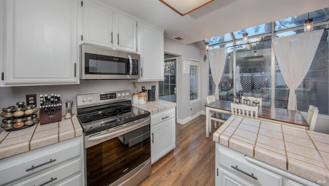 kitchen featuring stainless steel appliances, visible vents, white cabinetry, light wood-type flooring, and tile counters