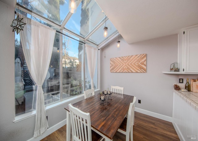 dining area featuring a sunroom, baseboards, and wood finished floors