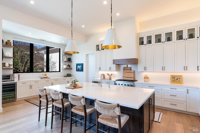 kitchen with beverage cooler, a sink, light wood finished floors, and open shelves