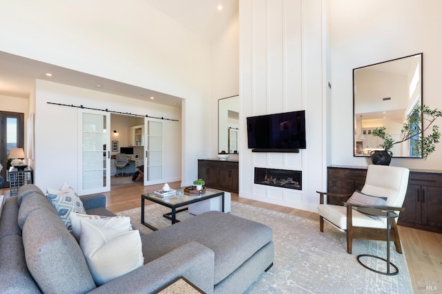 3878 Horizon View Way, Santa Rosa, CA 95404 - living room featuring light wood-style floors, a barn door, a high ceiling, a large fireplace, and recessed lighting