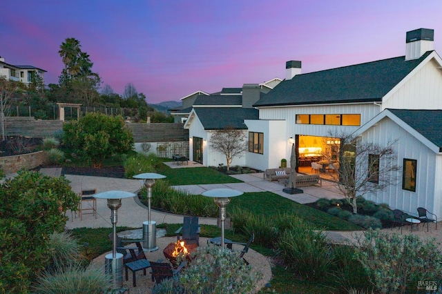 3878 Horizon View Way, Santa Rosa, CA 95404 - back of house at dusk featuring a patio, an outdoor fire pit, roof with shingles, a chimney, and board and batten siding