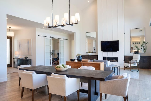 3878 Horizon View Way, Santa Rosa, CA 95404 - dining space featuring a high ceiling, light wood finished floors, a barn door, a chandelier, and a fireplace