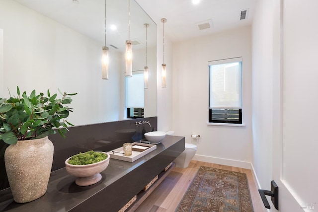 bathroom with baseboards, visible vents, toilet, and wood finished floors