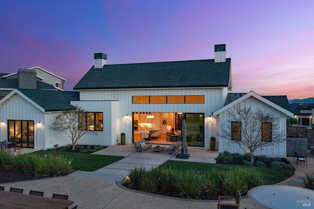 back of house featuring a chimney, board and batten siding, and a patio