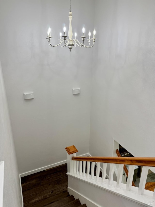 stairway with an inviting chandelier, baseboards, and wood finished floors