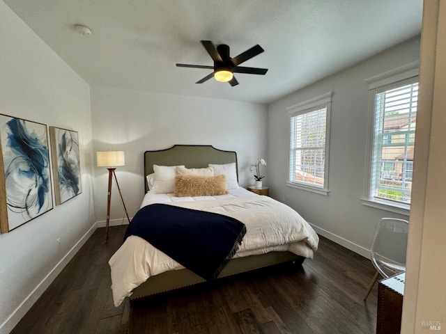 bedroom with dark wood-type flooring, a ceiling fan, and baseboards