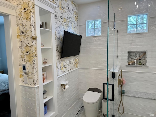 ensuite bathroom featuring a healthy amount of sunlight, a stall shower, built in features, and a wainscoted wall