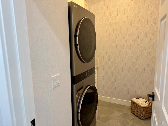 clothes washing area with laundry area, baseboards, and stacked washer / drying machine