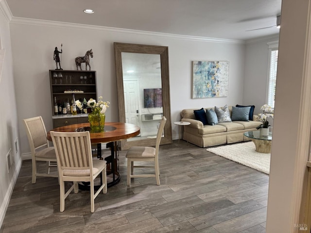 dining space featuring baseboards, wood finished floors, visible vents, and crown molding