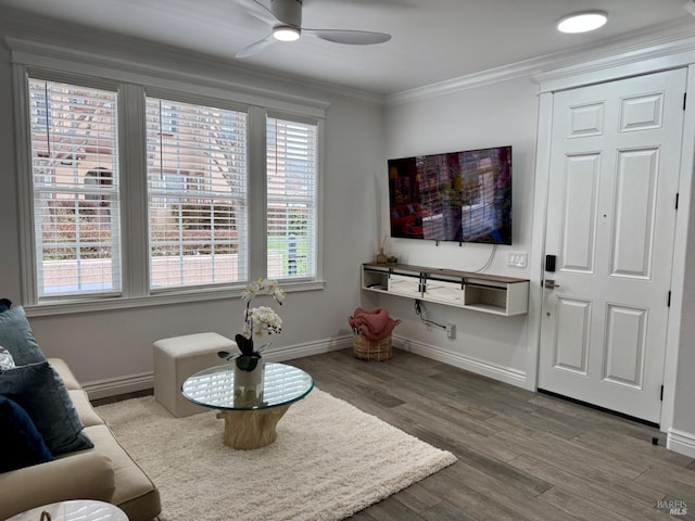 living area featuring ornamental molding, wood finished floors, a ceiling fan, and baseboards