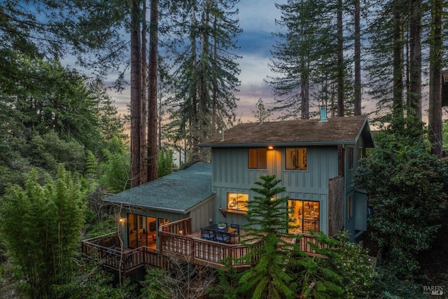 back of property at dusk with board and batten siding and a wooden deck