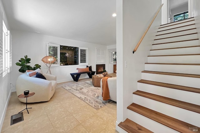 living room with a lit fireplace, visible vents, stairway, and baseboards