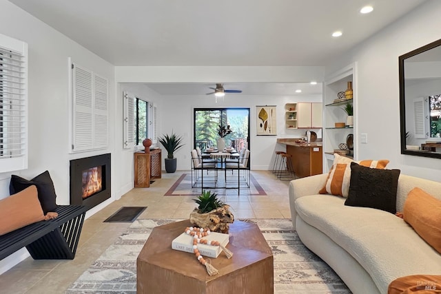 living room with light tile patterned floors, baseboards, a ceiling fan, a glass covered fireplace, and recessed lighting