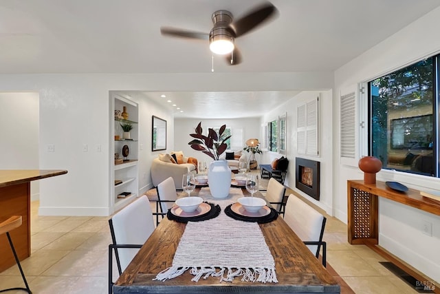 dining space with a warm lit fireplace, light tile patterned floors, baseboards, and built in features