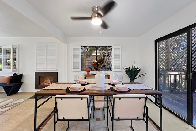 dining space with a lit fireplace and a ceiling fan