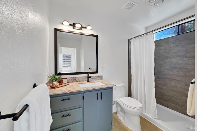 bathroom with toilet, visible vents, vanity, tiled shower, and tile patterned floors