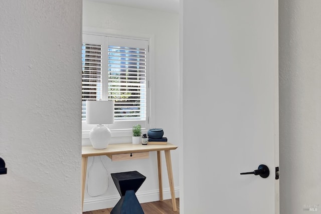 home office featuring a textured wall, wood finished floors, and baseboards