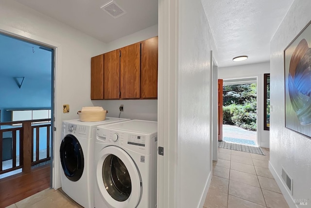 laundry area featuring light tile patterned floors, separate washer and dryer, visible vents, baseboards, and cabinet space